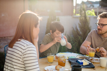 boy drinking milk while having breakfast with family at home