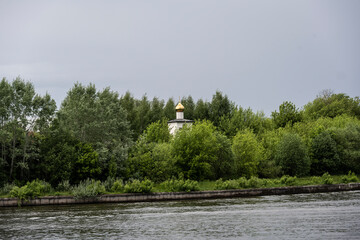 summer landscape with ancient churches against the backdrop of a forest and a river on a sunny day