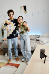 Full length portrait of two gen Z teenagers filming video for social media, boy and girl posing for...