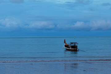 Fishing boat floating in calm sea near sandy beach.