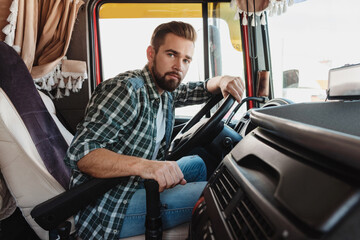 Young professional truck driver sitting inside his vehicle