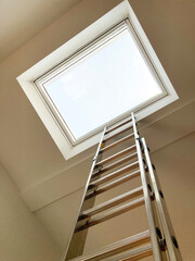 Leiter strebt hoch hinaus zu einem hellen Dachfenster 