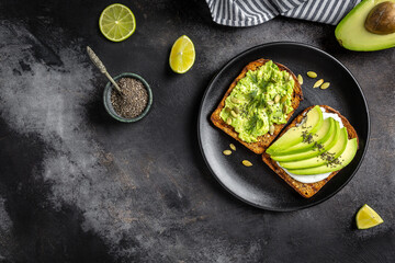 Healthy avocado toasts for breakfast or lunch with rye bread, sliced avocado, arugula, pumpkin and sesame seeds, salt and pepper. Vegetarian food. Plant-based diet. Clean eating. Top view. Copy space.