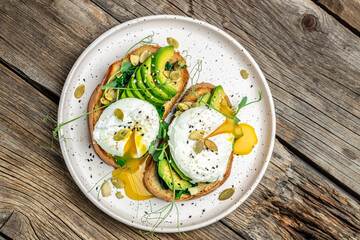 Poached egg on on bread with spinach, avocado and pumpkin seeds, Healthy food, keto diet, diet lunch concept. Top view