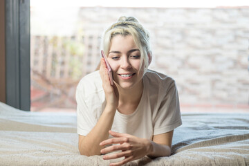 Young beautiful smiling woman talking on phone at home