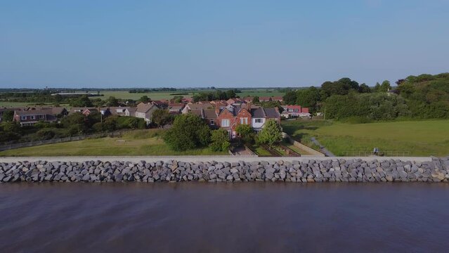 Drone shot mavic mini 2. Coastal flood defenses, English coastal village, houses, suburban. Filmed Yorkshire. England. 16.6.2022