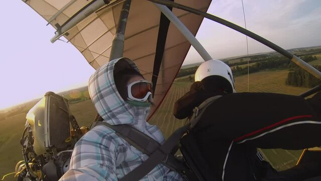 a couple flies on a hang glider against the sunset