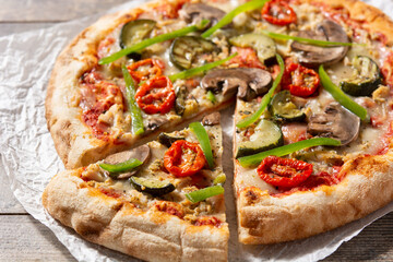 Vegetarian pizza with zucchini, tomato, peppers and mushrooms on wooden table	
