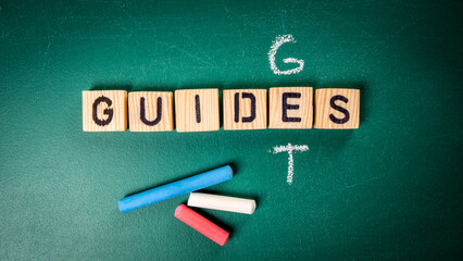 Get Guides concept. Wooden alphabet letters and chalk pieces on the blackboard