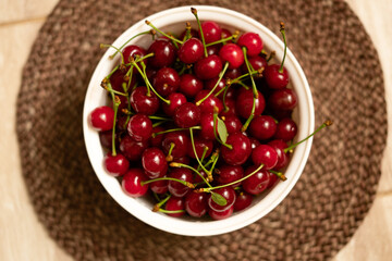 Close up of many ripe red cherries in a white bowl.