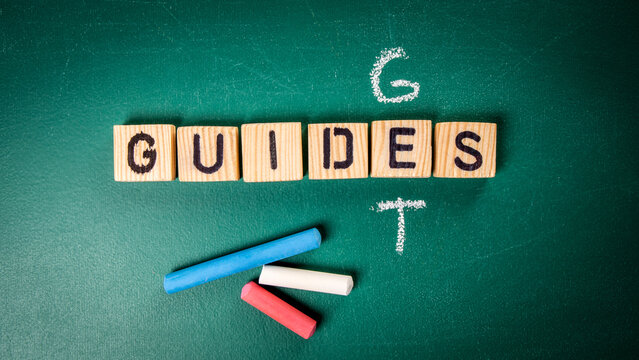 Get Guides concept. Wooden alphabet letters and chalk pieces on the blackboard