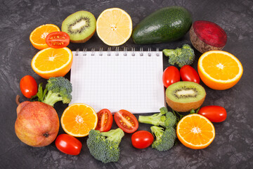Notepad and fruits with vegetables containing natural vitamins and minerals, slimming and diet concept