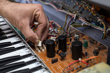 Latin American electronic technician fixes a piano in the service center. Concept repair, Music, electronic
