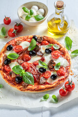 Crunchy pizza Capricciosa made of tomatoes, olives, cheese and ham.