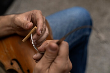 Top view of a Latin American luthier placing in a special tool a sound post that is placed inside the instrument by pressure between the top and the bottom of the violin. Stringed instruments concept