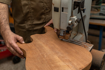Close-up of unrecognizable Latin American luthier making an electric guitar with a saw. Stringed instrument construction concept