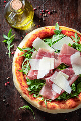 Tasty and healthy pizza Parma with prosciutto, parmesan and arugula.