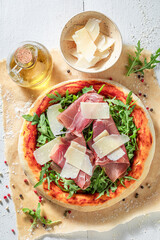 Crunchy pizza Parma made of prosciutto ham, parmesan and arugula.