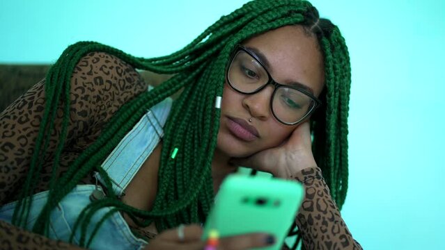 A black girl staring at phone screen An African American young woman looking at smartphone device