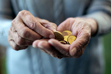 older womans hand holding coins and counting - obrazy, fototapety, plakaty