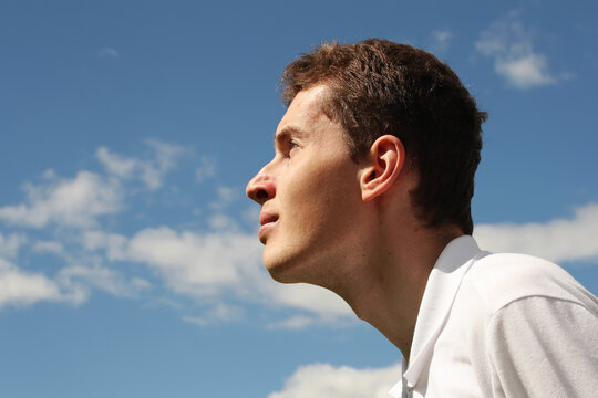 Young man face profile on a blue sky background. Photo was taken 15 June 2022 year, MSK time in Russia.