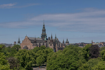Fototapeta na wymiar Old gothic museum building with towers and spires and the skyline of the districts Östermalm and Vasastan a sunny summer day in Stockholm 