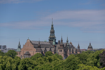 Fototapeta na wymiar Old gothic museum building with towers and spires and trees a sunny summer day in Stockholm 