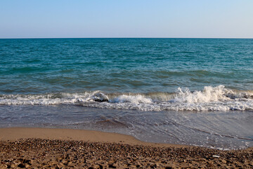 Beautiful seascape. Sea coast with pebbles and sea waves. The concept of summer vacation and...