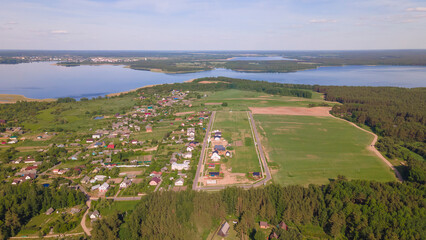 Fototapeta na wymiar Aerial view of lake and small village. Village near the lake. Aerial view of the village and trees on the shore of lake.