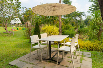 Relax table, chairs and umbrellas in park garden. Outdoor restaurant