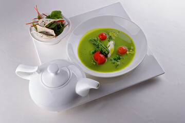 Cream soup of green peas with tomatoes, on a white background