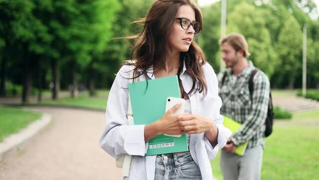 Portrait of college friends with books in campus park after classes. Friendship in university.