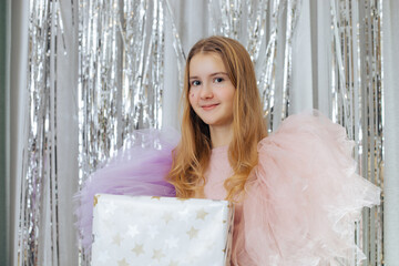 Cute smiling teenage girl in festive outfit with puffy chiffon sleeves of pink and lilac color...