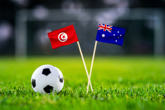 October 2022: Tunisia vs Australia, Al Janoub Stadium, Football match wallpaper, Handmade national flags and soccer ball on green grass. Football stadium in background. Black edit space.