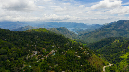 Fototapeta na wymiar Top view of Mountain slopes with rainforest and a mountain valley with farmland. Sri Lanka.
