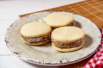 Classic Argentinean cornstarch and dulce de leche alfajores with coconut on a vintage plate. high view. sweet snack