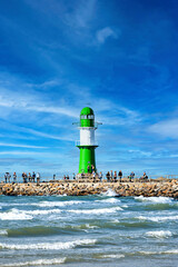 Lighthouse at the harbor entrance from the Baltic Sea to Warnemuende and Rostock with tourists on...