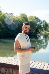 Young handsome men look at camera taking phone with his hand listening music with headphones smiling