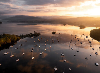 Sunrise on Lake Windermere above a marina. Floating boats and beautiful reflections