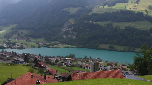 Stunning turquoise Lake Lungerersee with clear water, Landscape view of the roofs of traditional swiss houses, green meadows, lawn. Incredibly bewitching and calm place.