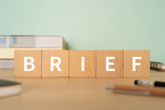 要約・簡潔のイメージ｜「BRIEF」と書かれたブロックが置かれたデスク
