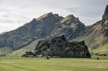 Skogar, Iceland, April 22, 2022: monolithic rock with traditional houses and barns built in of against it