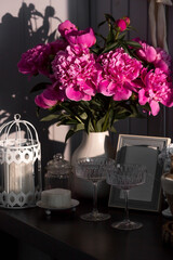 A beautiful pink bouquet of peonies in the sunlight on a black table. The interior of a country house in the style of Provence. The concept of home comfort and decor in the house.