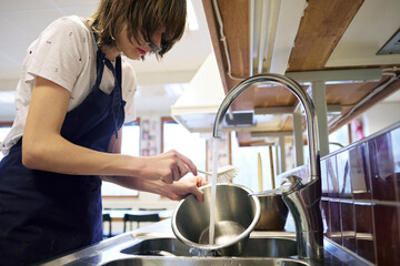 Young woman in kitchen washing dishes
