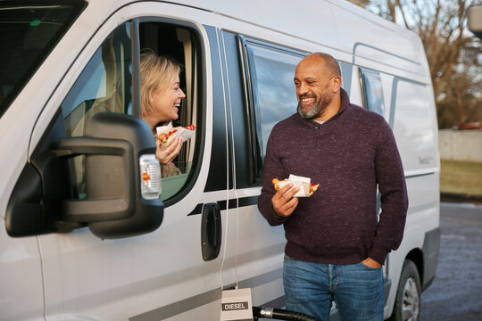 Couple Eating Hot Dog At Gas Station