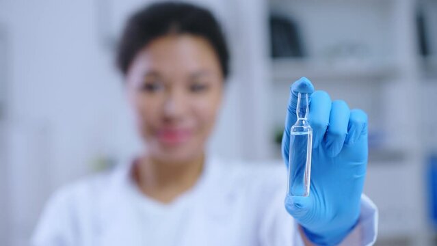 Successful lab technician showing medical ampoule, cancer drug development