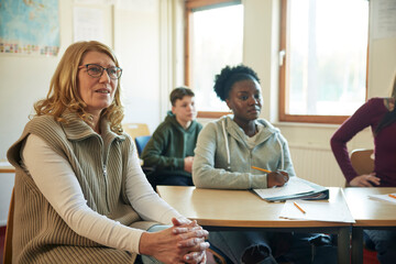Group of students and teacher sitting in class
