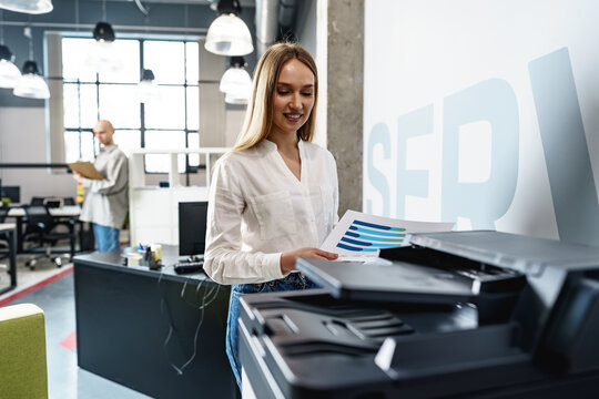 Young Employee Using Modern Printer In Office