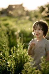 a boy in the park on the playground in the sandbox plays with sand and a shovel. happy child on a walk on a summer evening