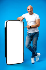 Middle-aged man standing and showing big smartphone with blank white screen
